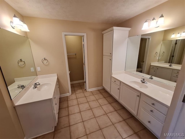 bathroom with tile patterned floors, vanity, toilet, and a textured ceiling