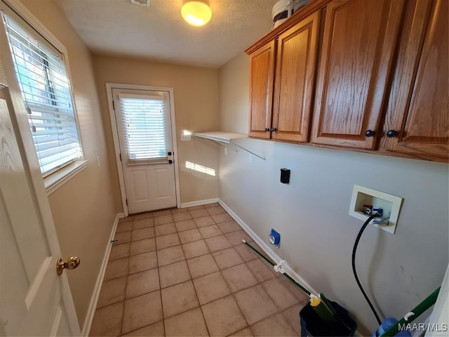 washroom with washer hookup, hookup for a gas dryer, light tile patterned flooring, and cabinets