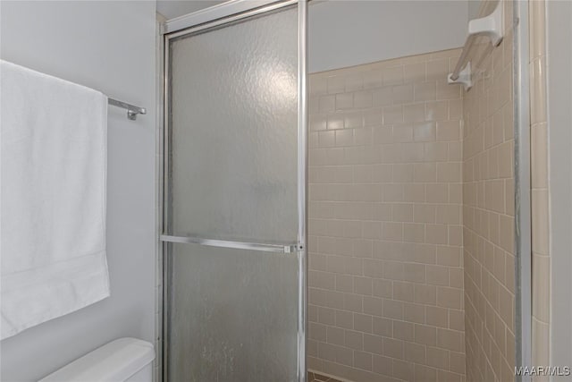 bathroom featuring toilet and a shower with shower door