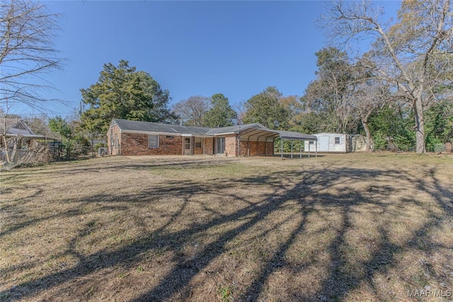 ranch-style home featuring a front lawn, a carport, and an outdoor structure