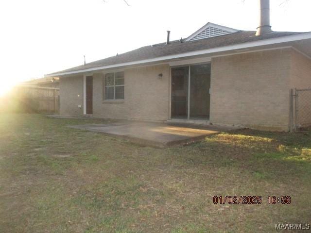 rear view of property with a patio and a lawn