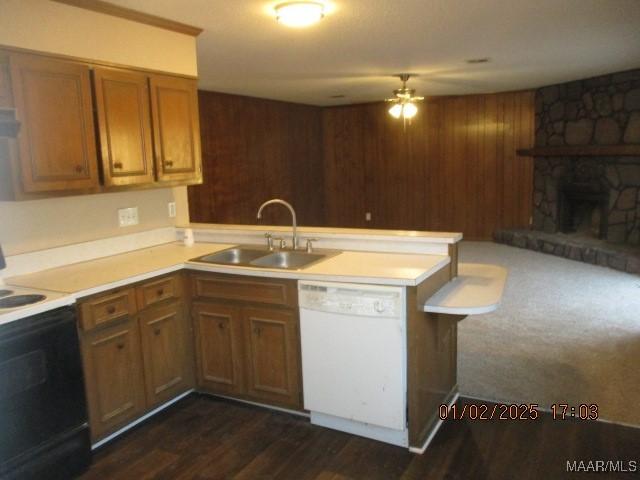 kitchen with kitchen peninsula, white appliances, ceiling fan, sink, and a fireplace