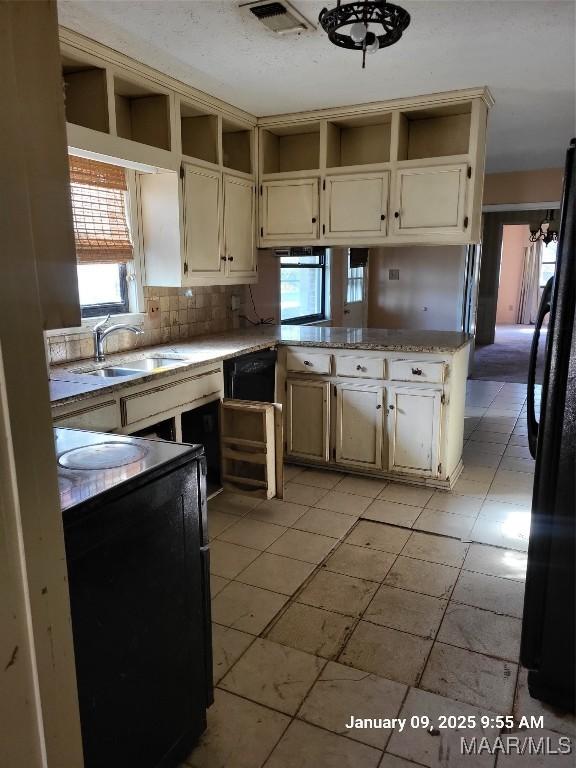 kitchen with visible vents, stove, freestanding refrigerator, white cabinetry, and a sink