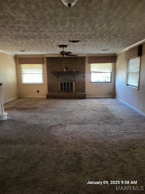 unfurnished living room with carpet floors, a healthy amount of sunlight, a fireplace, and a ceiling fan