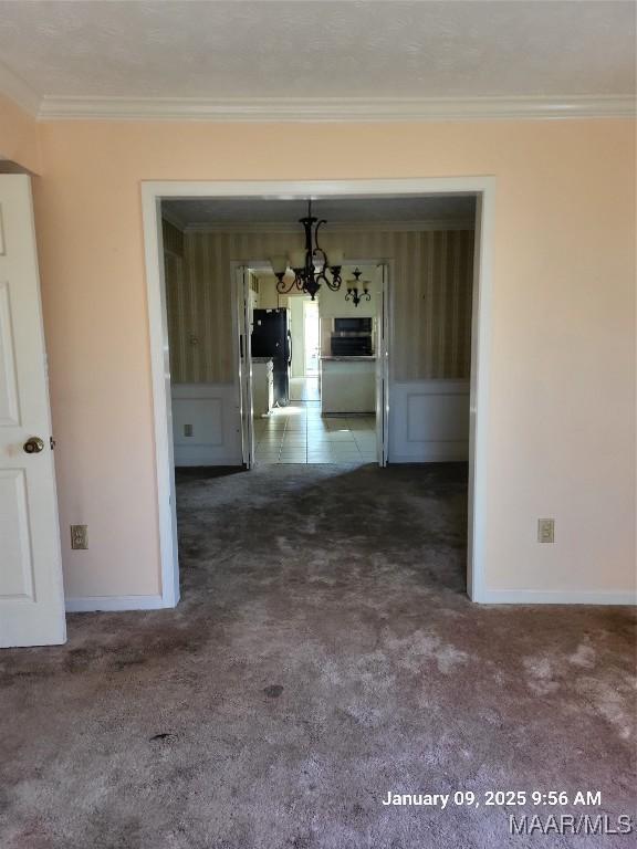 interior space featuring baseboards, carpet floors, an inviting chandelier, and crown molding