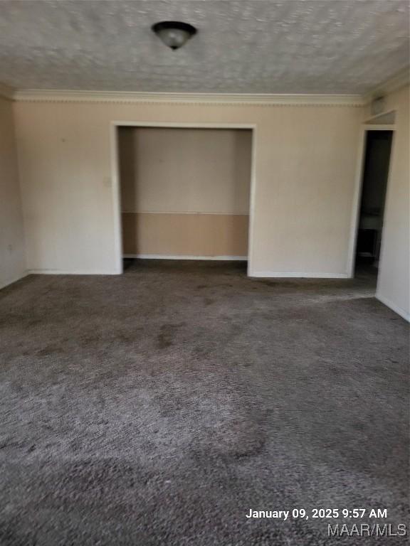 unfurnished bedroom with a textured ceiling, carpet floors, ornamental molding, and a closet