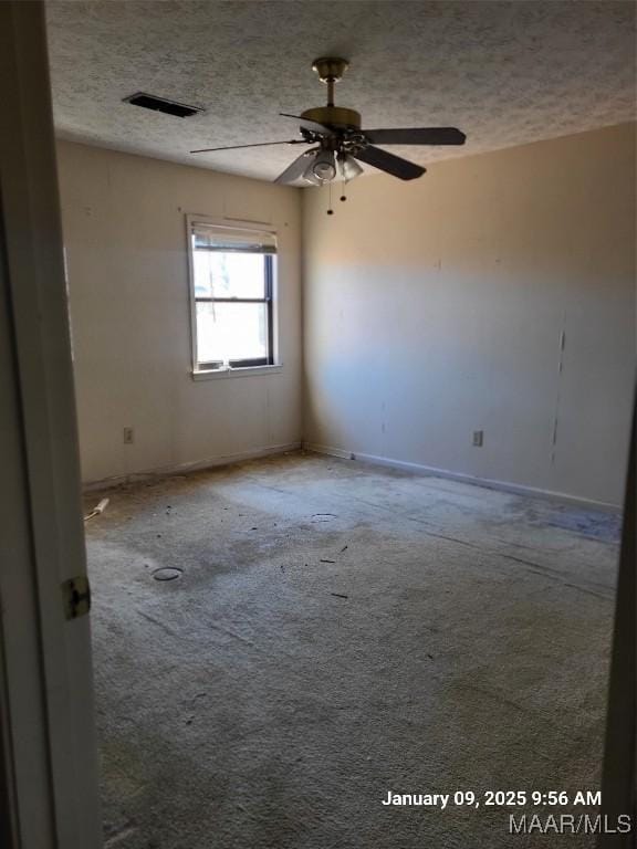 carpeted spare room featuring a ceiling fan, visible vents, a textured ceiling, and baseboards