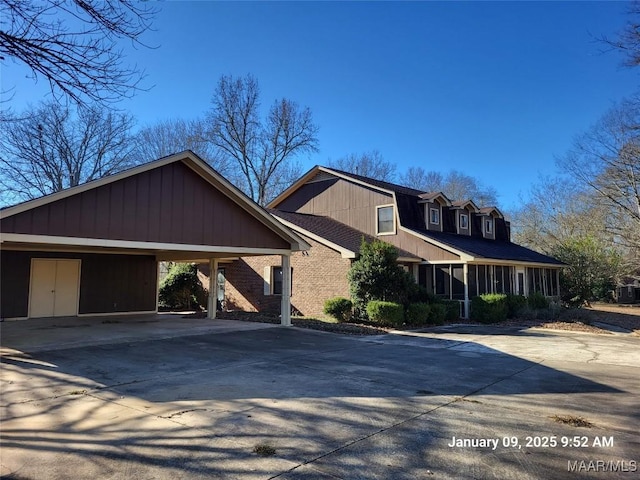 view of front of house featuring a carport, brick siding, driveway, and roof with shingles