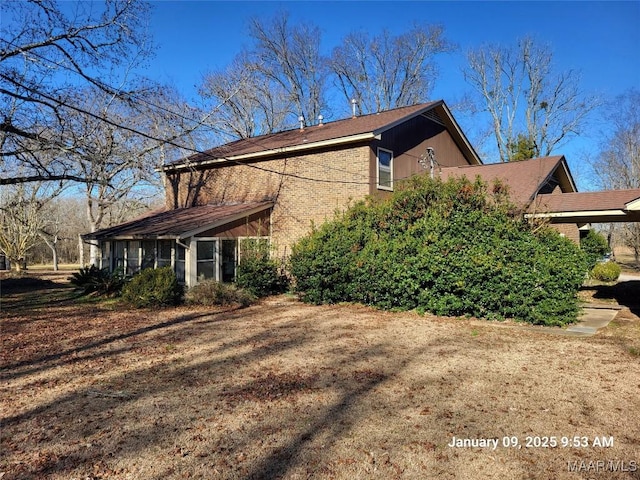 view of side of property featuring a sunroom and brick siding