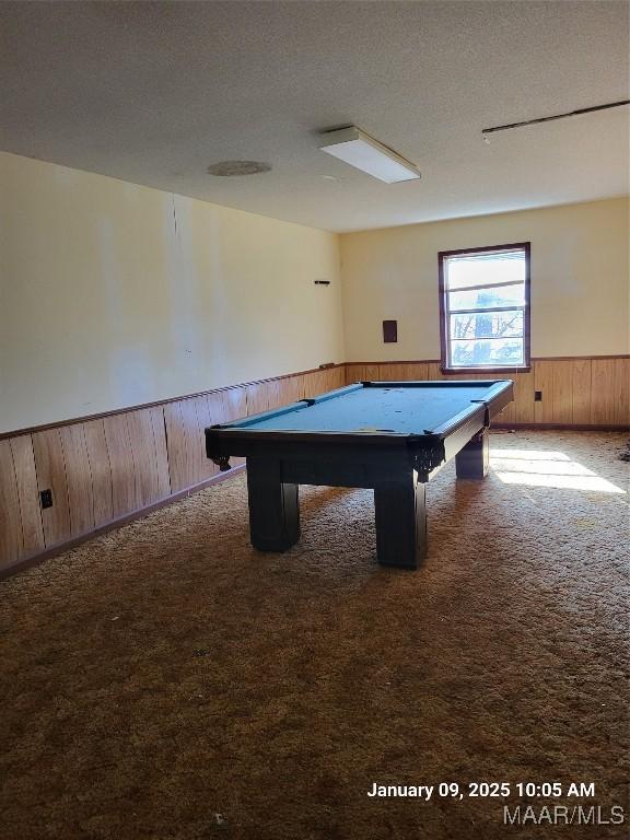 game room with carpet, a wainscoted wall, wood walls, and a textured ceiling