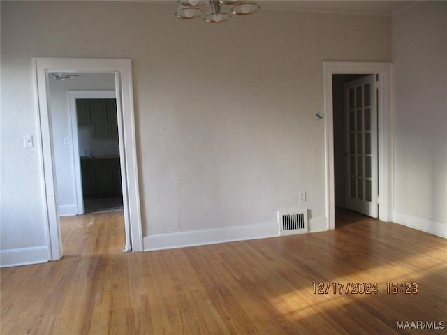 unfurnished room with light wood-type flooring and a notable chandelier