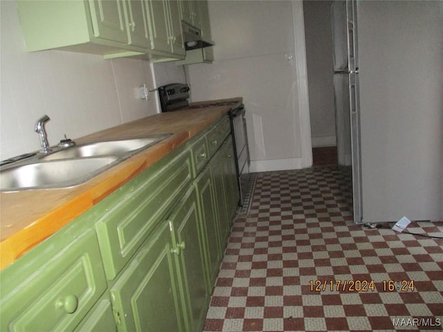 kitchen featuring wooden counters, black range with electric cooktop, sink, stainless steel refrigerator, and green cabinets