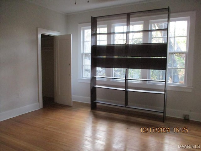 empty room with hardwood / wood-style floors, a healthy amount of sunlight, and crown molding