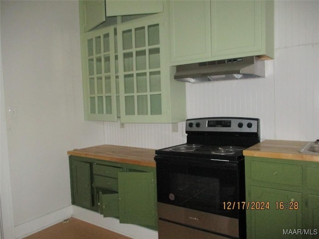 kitchen with wood counters, stainless steel electric range, green cabinetry, and exhaust hood