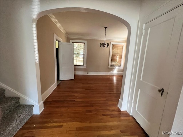 hall featuring ornamental molding, dark hardwood / wood-style floors, and an inviting chandelier