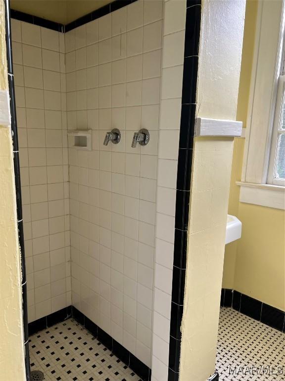 bathroom with tile patterned flooring and a tile shower