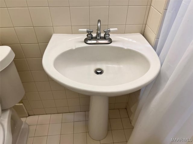 bathroom with tile patterned flooring, toilet, and tile walls