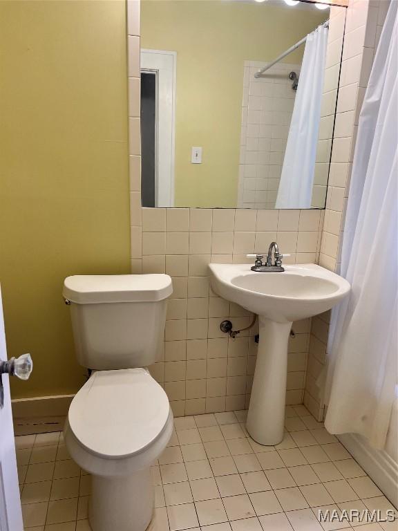 bathroom featuring toilet, a shower with curtain, and tile patterned floors