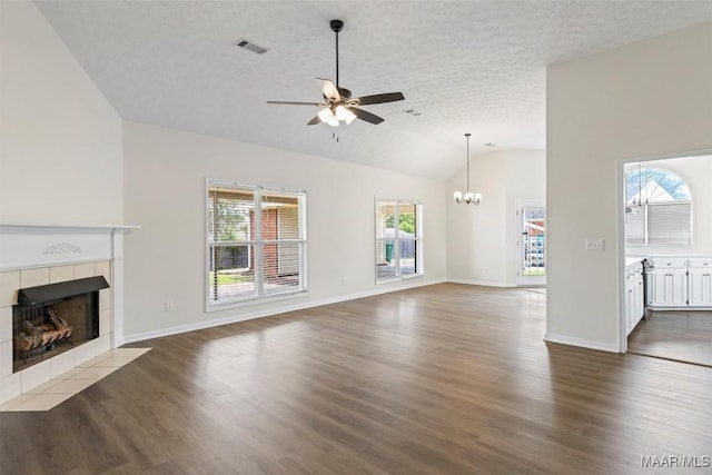 unfurnished living room featuring plenty of natural light, a fireplace, ceiling fan with notable chandelier, and lofted ceiling