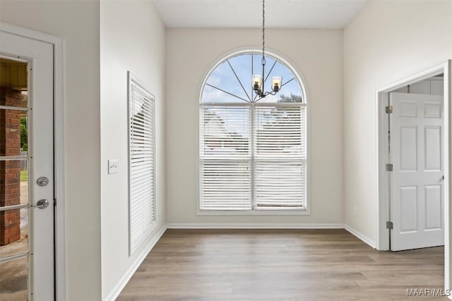 unfurnished dining area featuring light hardwood / wood-style flooring and a notable chandelier