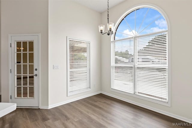 unfurnished dining area featuring hardwood / wood-style floors and a chandelier