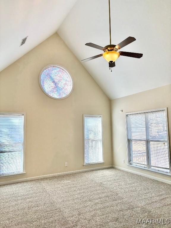 carpeted empty room featuring ceiling fan, a healthy amount of sunlight, and high vaulted ceiling