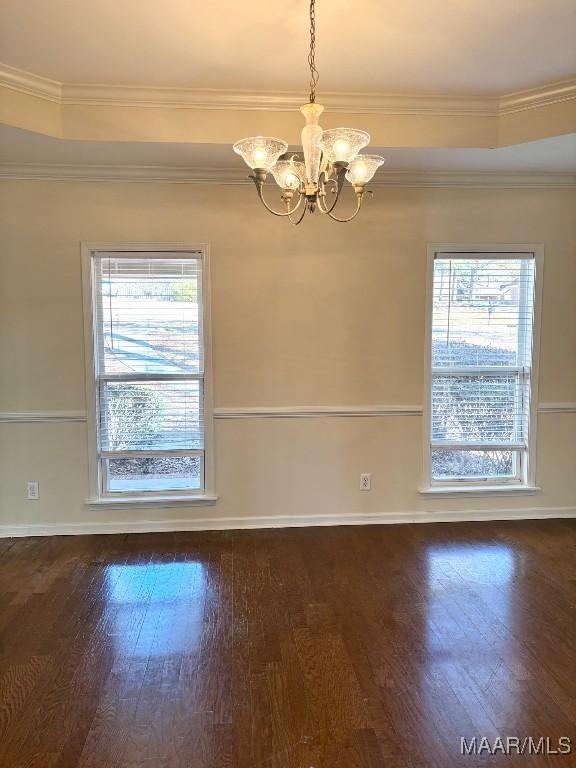 unfurnished room featuring a raised ceiling, ornamental molding, dark hardwood / wood-style floors, and a notable chandelier