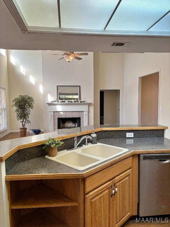 kitchen featuring dishwasher, ceiling fan, sink, and a tile fireplace