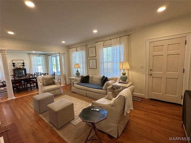 living room featuring ornate columns, plenty of natural light, and wood-type flooring