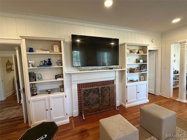 living room with hardwood / wood-style flooring, crown molding, and a fireplace