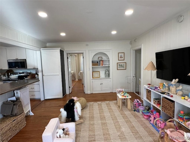 playroom with built in features, ornamental molding, and hardwood / wood-style flooring