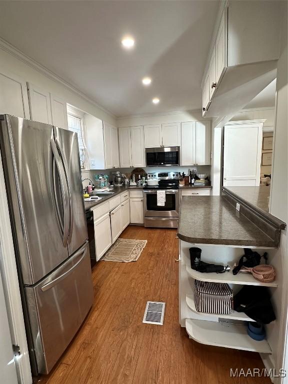 kitchen with sink, dark hardwood / wood-style flooring, white cabinets, and appliances with stainless steel finishes