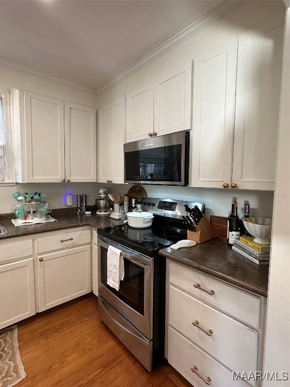 kitchen featuring white cabinets, stainless steel appliances, crown molding, and light hardwood / wood-style floors