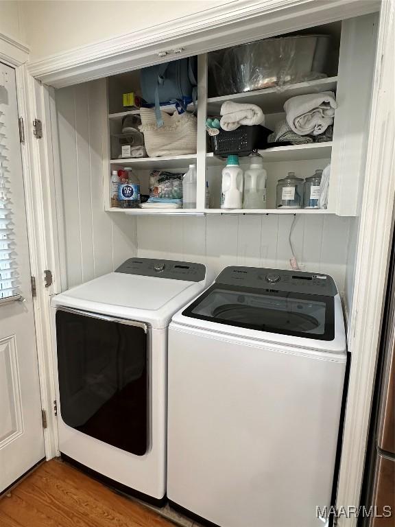 laundry room featuring washing machine and clothes dryer and hardwood / wood-style flooring