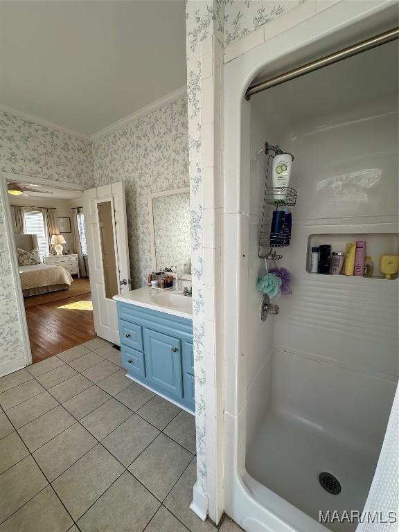 bathroom featuring a shower, tile patterned flooring, vanity, and crown molding