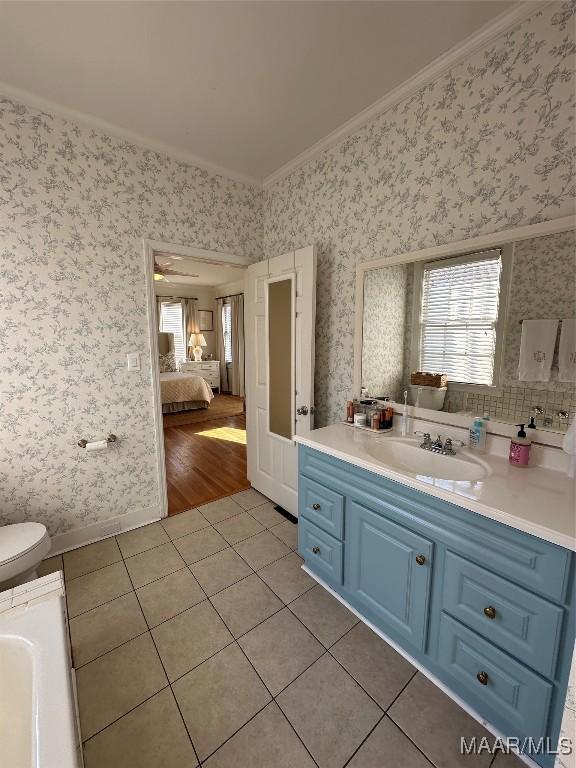 bathroom featuring tile patterned flooring, vanity, toilet, and ornamental molding