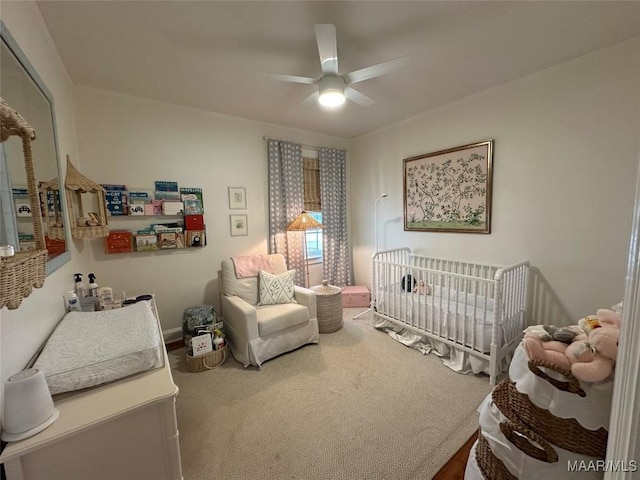 bedroom with a nursery area and ceiling fan