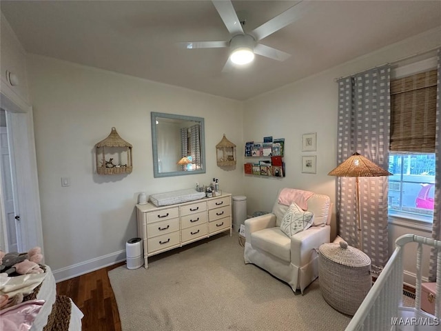 bedroom with ceiling fan, dark hardwood / wood-style flooring, and a nursery area