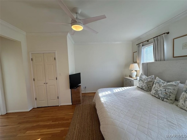 bedroom with ceiling fan, a closet, crown molding, and wood-type flooring