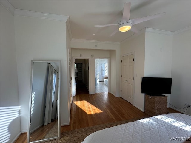 bedroom with ceiling fan, wood-type flooring, crown molding, and a closet