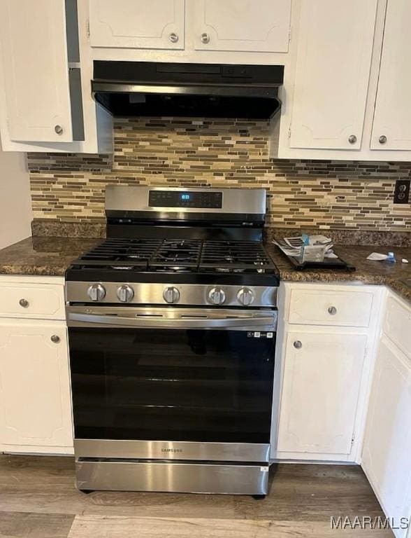 kitchen featuring hardwood / wood-style floors, decorative backsplash, white cabinetry, and gas range