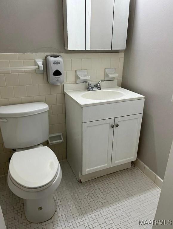 bathroom featuring tile patterned floors, vanity, tile walls, and toilet