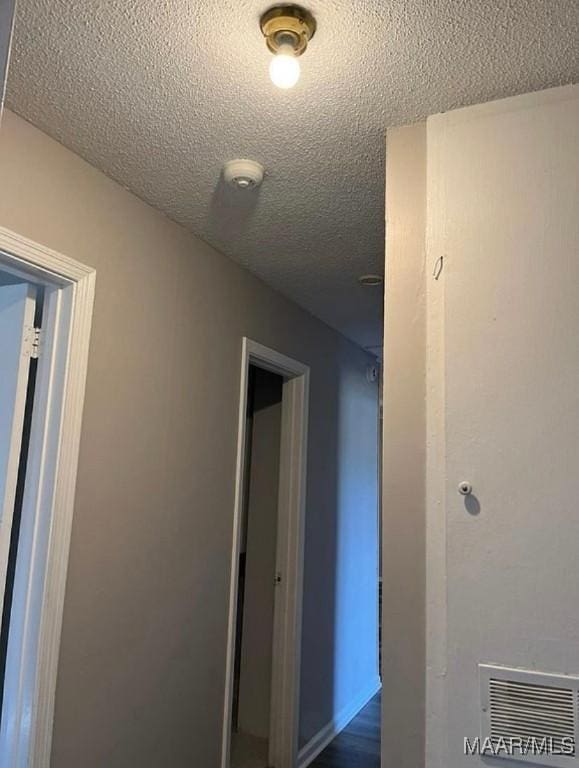 corridor featuring wood-type flooring and a textured ceiling