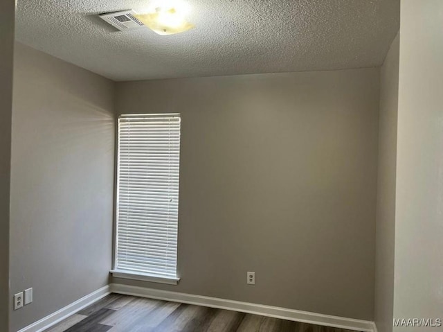 empty room featuring dark hardwood / wood-style flooring and a textured ceiling