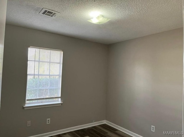 empty room with a textured ceiling and dark wood-type flooring