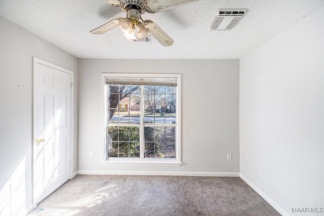 spare room featuring light carpet, ceiling fan, and a textured ceiling