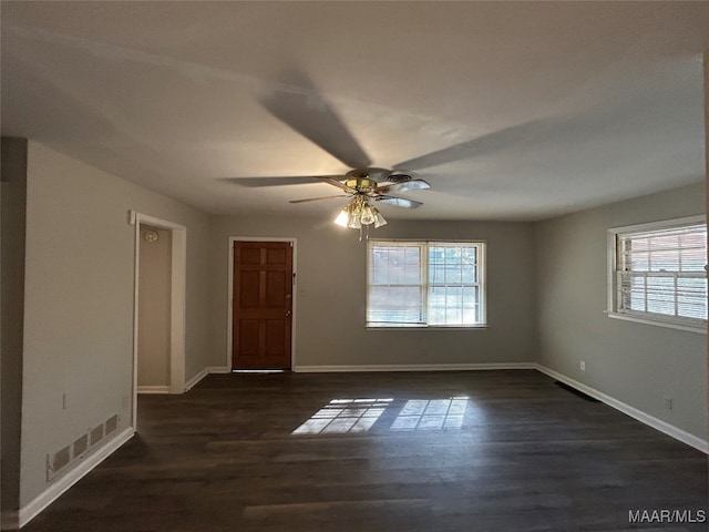 empty room with dark hardwood / wood-style floors, ceiling fan, and a healthy amount of sunlight