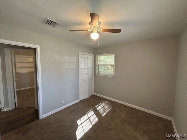 unfurnished bedroom with dark colored carpet, a closet, and ceiling fan