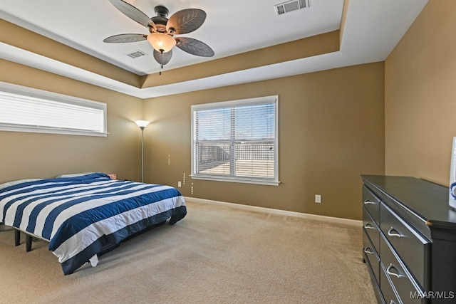 bedroom featuring ceiling fan, a raised ceiling, and light carpet