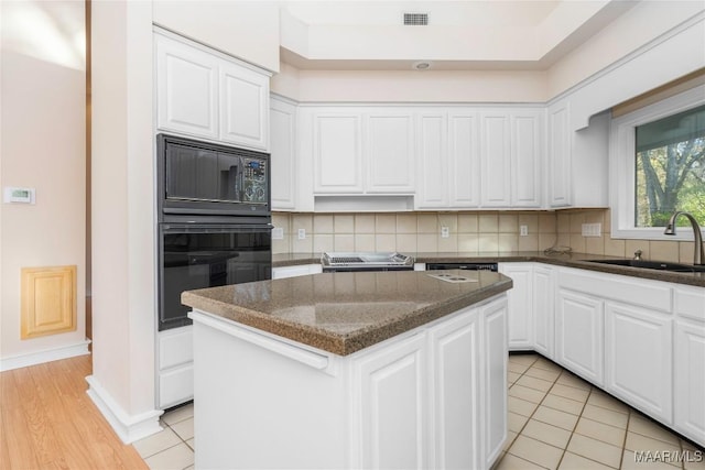 kitchen with decorative backsplash, sink, black appliances, white cabinets, and a center island